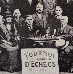 Zooming in on the photo. From left to right: Mrs Holloway (England - 1st woman to play an Olympiad), Edgar Colle (Belgium), Alexandre Alekhine, Pierre Vincent, Jonet (Belgium), Lucien Sauphar (Mayor of the IXth arrondissement)